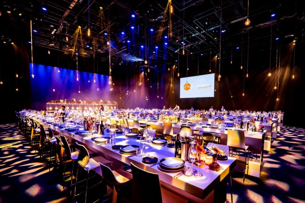 Lange gedekte dinertafel in een feestelijk verlichte zaal bij Hart van Holland